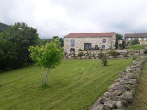 a house in a field with a tree and a stone wall at La clé des Champs in Roche