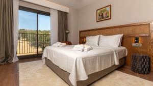 a bedroom with a large white bed with a balcony at Cunda Kızılca Deluxe Hotel & SPA in Ayvalık