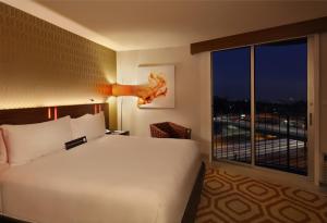a bedroom with a large bed and a large window at Hotel Angeleno in Los Angeles