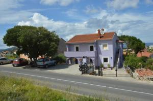 a white house on the side of a road at Apartmani Raić in Mali Lošinj