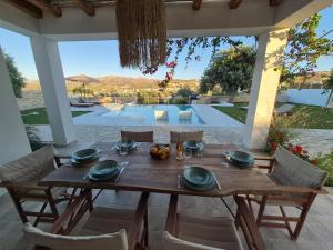 a wooden table on a patio with a view of a pool at Villa Neroli Pool & Mountain Views in Pitsidia in Pitsidia