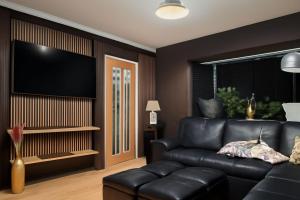 a living room with a black leather couch and a flat screen tv at Smile House Doncaster in Doncaster