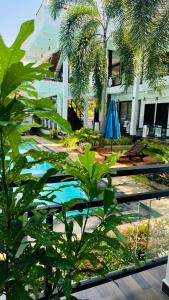 a pool in front of a building with a blue umbrella at J7 Villaj Resort in Trincomalee