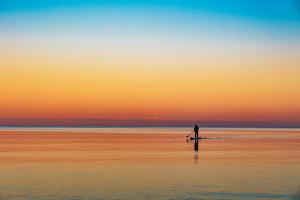 a person walking on the beach at sunset at Hotel Leuchtturm in Timmendorfer Strand