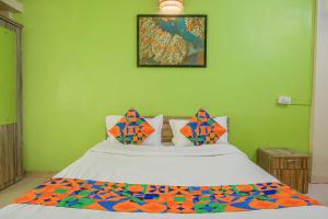 a green bedroom with a bed with a colorful comforter at FabHotel Saraswati Niwas in Pune