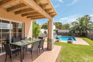 Un patio con mesa y sillas y una piscina. en Villa Judith En Menorca, en Son Carrio