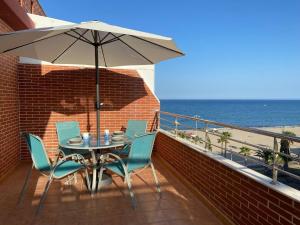 een terras met een tafel, stoelen en een parasol bij Brisamarina Playa Apartamento in Roquetas de Mar