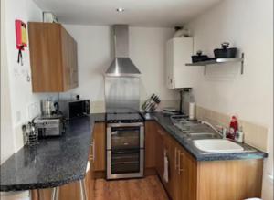 a kitchen with black counter tops and wooden cabinets at 34 - Room 3 - Uplands in Swansea