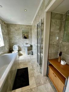 a bathroom with a tub and a sink at Spacious Ensuite Room With Garden View in Dagenham