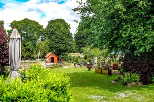 a garden with an umbrella and a cabin in the background at Richtenberger Ente Apartments Ferienwohnungen in Richtenberg