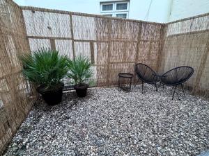a patio with two chairs and plants in front of a fence at Regency Haven in London