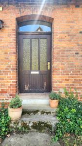 eine Holztür mit zwei Töpfen vor einem Backsteingebäude in der Unterkunft Cosy Cottage Rooms near Autobahn A2 & Hannover in Barsinghausen + 7 Fotos