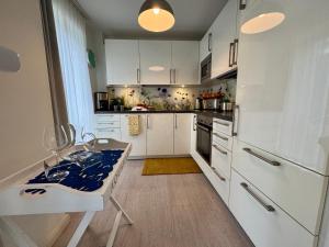 a kitchen with white cabinets and a table in it at Aquamarin Ostseetraumsuite 05 in Neuhaus