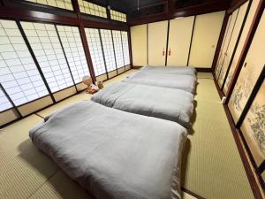 a row of beds in a room with windows at 一棟貸し古民家赤ちゃんから楽しめる文化庁選定重要伝統的建造物 築130年"古民家ゆうなぎ"小松空港から35分 金沢から60分 in Kaga