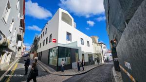 ポンタ・デルガダにあるApartamento Sonho Brisaの白い建物の外に立つ人々