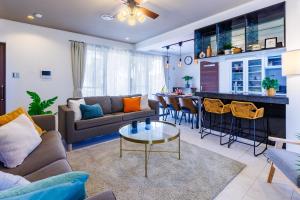 a living room with a couch and a table at 最大16名 BBQ可能 駐車場3台 シアタールーム付きのグループ旅行におすすめ宿 The MELIA in Yomitan