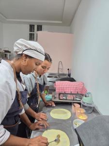 Dos mujeres en una cocina preparando comida en una mesa. en atelier de cuisine, en Marrakech