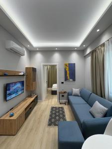 un salon avec un canapé bleu et une télévision dans l'établissement glenz apartments, à Vlorë