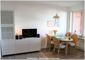 a dining room with a tv and a table with chairs at Hafenblick Orth in Orth