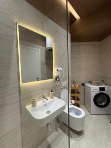 une salle de bain avec un lavabo, des toilettes et un miroir dans l'établissement glenz apartments, à Vlorë