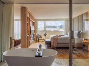 a hotel room with a tub and a bedroom at ME Lisbon by Meliá in Lisbon +58 photos