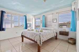 a bedroom with a bed with blue curtains and windows at Vista del Mar Apt C- 2 min in car from Sandy Beach in Rincon +9 photos