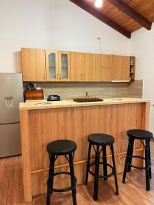 a kitchen with three bar stools and a refrigerator at Pensiunea Belleview in Sibiu
