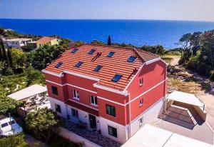 a large red house with a red roof and the ocean at Apartments Villa Lukas in Cavtat