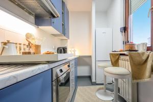 a kitchen with blue cabinets and a counter with a stool at Apartment Zagreb Spirit in Zagreb