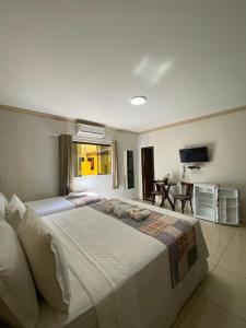 a large white bed in a bedroom with a television at Pousada Gamela do Maragogi in Maragogi