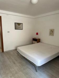 a white bedroom with a bed and a table at Appartamento in Villa in San Nicola
