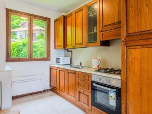 a kitchen with wooden cabinets and a stove top oven at Apartment Borgo Castello-5 by Interhome in Argegno