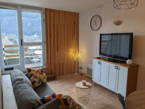 a living room with a couch and a flat screen tv at La Terrasse du Tarn in Ispagnac