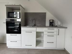 a kitchen with white cabinets and a stove and microwave at FeWo Büdingen - Atelier in Büdingen