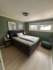 una camera da letto con un letto, una sedia e due finestre di Bright and Renovated Home 10 min to Kristiansand a Kristiansand