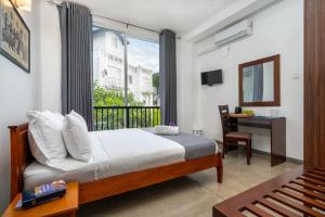 une chambre avec un lit, un bureau et une fenêtre dans l'établissement Mo Green, à Kandy