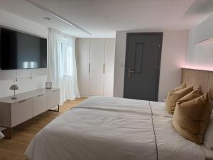 ein Schlafzimmer mit einem großen weißen Bett und einem Fernseher in der Unterkunft Oberbaar 7 in Baar