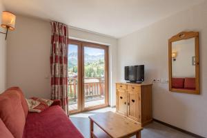 a living room with a couch and a tv and a window at Résidence Odalys Pra Sainte Marie in Vars