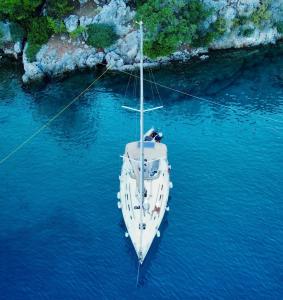 a white boat in the water next to a cliff at Nautical Nomads Yacht Charter in Tivat