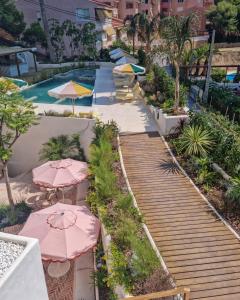 a wooden pathway with umbrellas and a swimming pool at Nomad Boutique Resort Benidorm in Benidorm