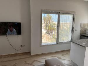 a room with a tv on a wall with a window at Djerba Apparts in Djerba