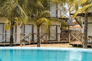 - une piscine avec deux palmiers en face d'un bâtiment dans l'établissement Apto 110 Taiti Villas BobZ, à Barrinha
