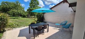 einen Tisch und Stühle mit einem blauen Regenschirm auf einer Terrasse in der Unterkunft Maison plein coeur de village in Villevieux