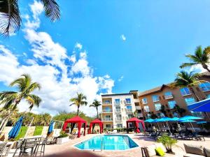 einen Pool mit Stühlen und Sonnenschirmen vor einem Hotel in der Unterkunft Holiday Inn Express & Suites Naples Downtown - 5th Avenue by IHG in Naples