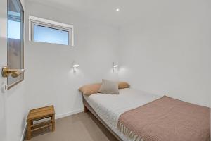 a small bed in a white room with a window at Where Lake Meets Forest in Dalsgårde