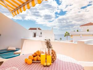 un tavolo con un piatto di frutta e due bicchieri di succo d'arancia di Apartamento cerca playa San Eugenio a Costa de Adeje