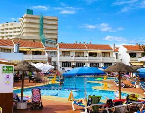 a swimming pool with chairs and umbrellas in a resort at Apartamento cerca playa San Eugenio in Costa de Adeje