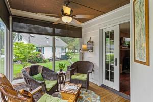 a screened in porch with chairs and a ceiling fan at Takundewide Retreat in Queensbury