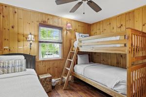 two bunk beds in a room with wooden walls at Takundewide Retreat in Queensbury