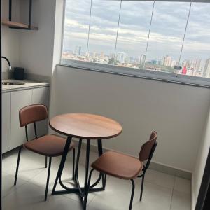 a table and two chairs in a kitchen with a window at Apartamento confortável – perto do centro de Bauru in Bauru +1 photo
